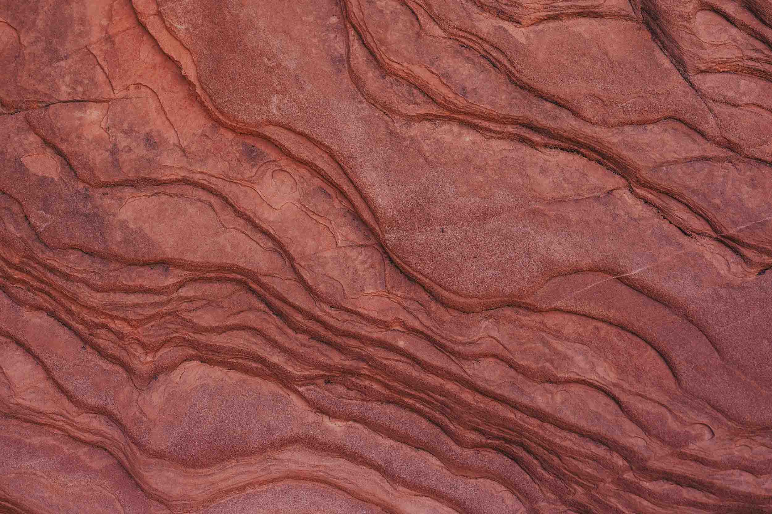 SANA wellness aesthetic – close-up of natural red rock texture with flowing layered patterns